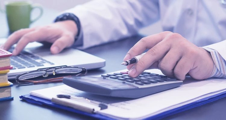 doctor-at-desk-with-calculator-ultrawide