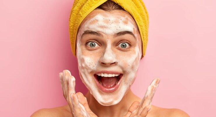 surprised-happy-woman-spreads-palms-near-face-has-joyous-expression-looks-herself-mirror-bathroom-washes-face-with-sanitary-soap_273609-32978