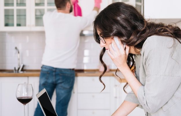 woman-using-laptop-while-man-cleaning_23-2147766964