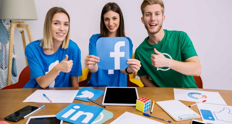 smiling-woman-holding-facebook-logo-with-his-friends-showing-thumbup-sign_11zon