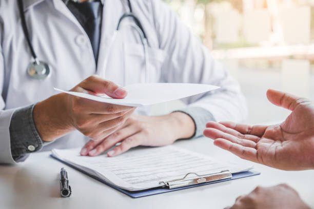 doctor-or-physician-writing-diagnosis-and-giving-a-medical-prescription-to-male-patient