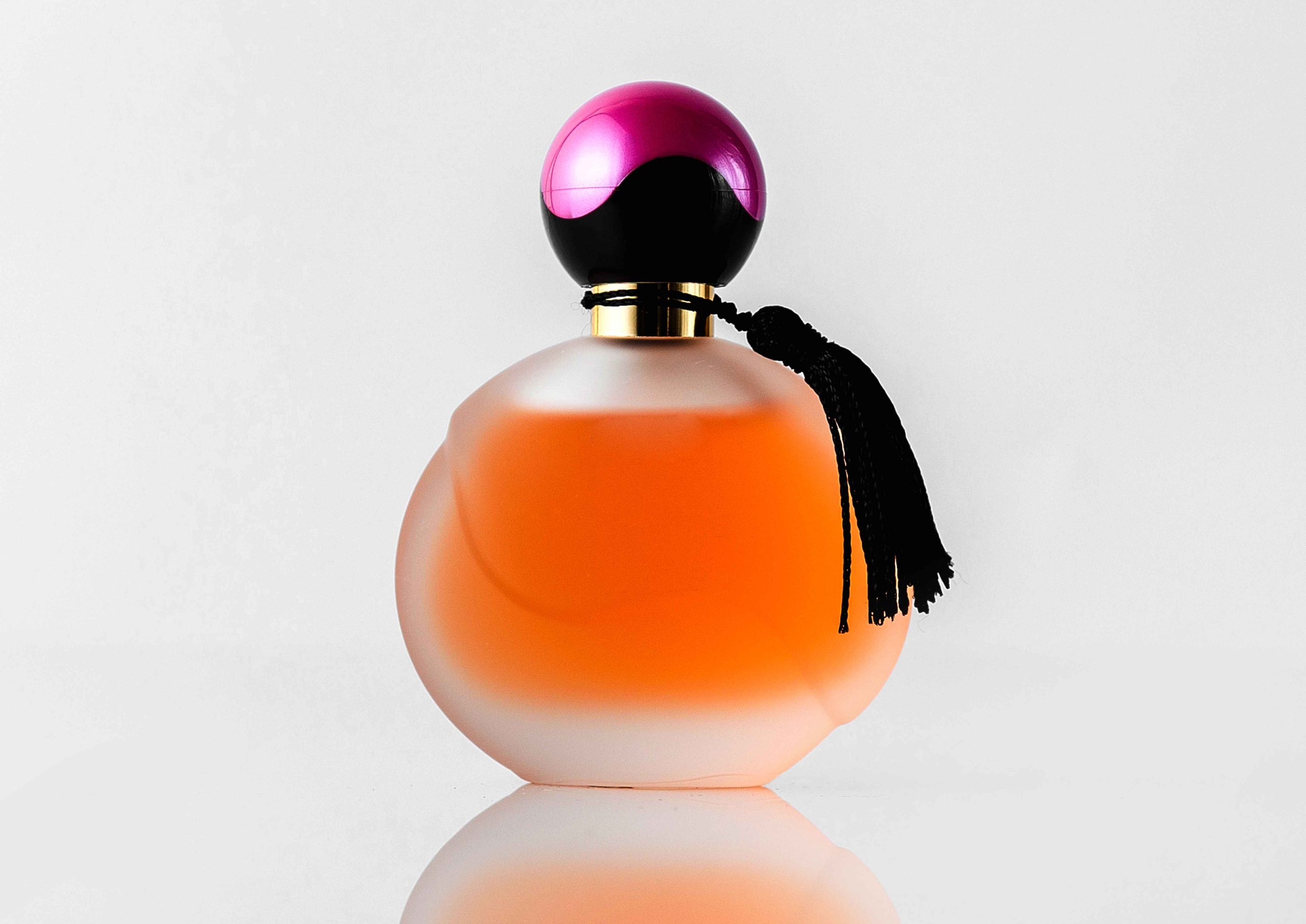 front-view-orange-designed-perfume-with-black-purple-cap-isolated-white-floor_11zon