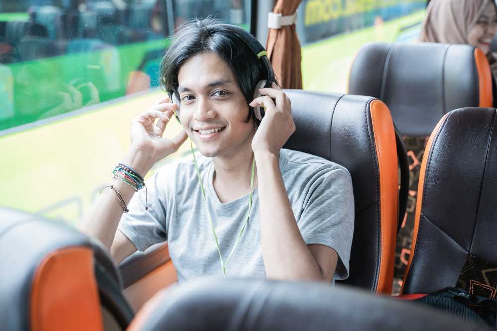 A young man in a bus, listening to music.